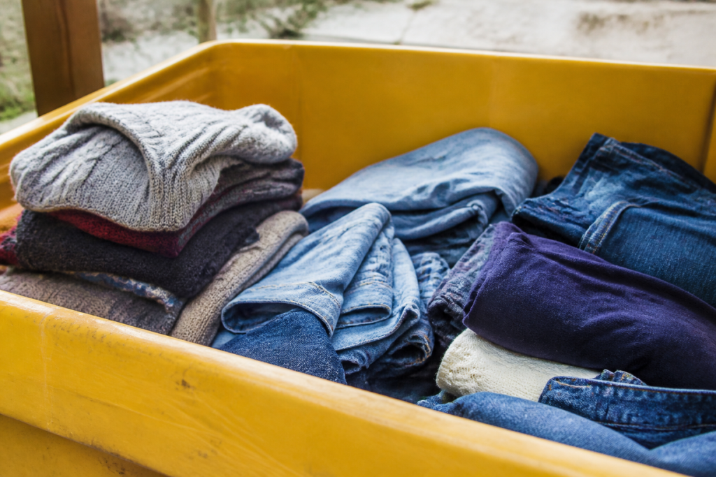 Pulls et jeans empiles dans un conteneur jaune